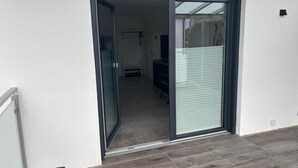 A sliding glass door leading to a room with a bed and a TV.
