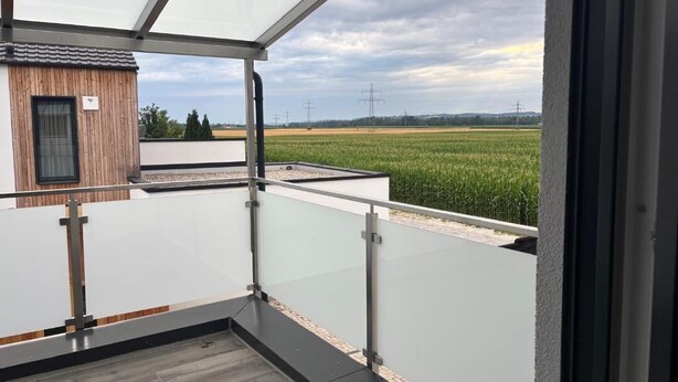 A balcony with a view of a green field and power lines.
