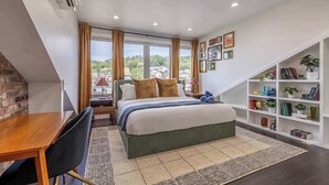A bedroom with a bed, a desk, a bookshelf, and a window with curtains.
