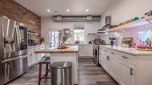 A modern kitchen with a central island, stainless steel appliances, and a neon sign.