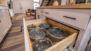 A kitchen with white cabinets, a wooden countertop, and a drawer with pots.