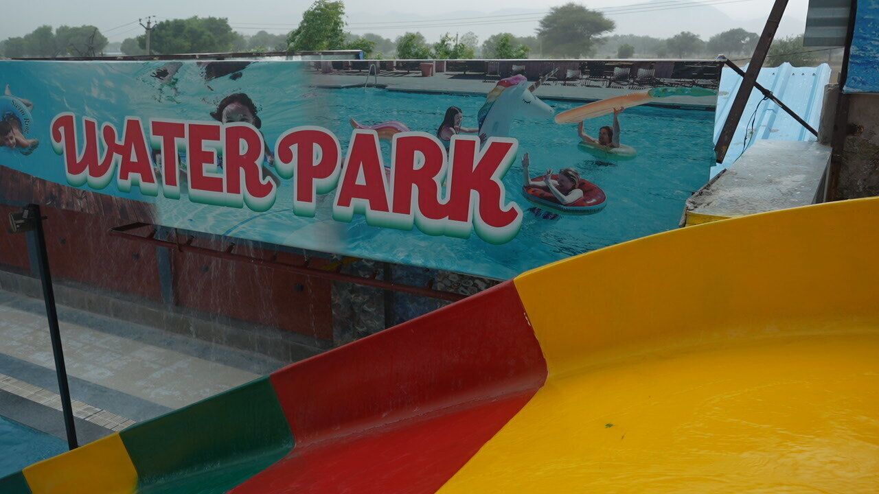 Un parco acquatico con una grande piscina e uno scivolo colorato.