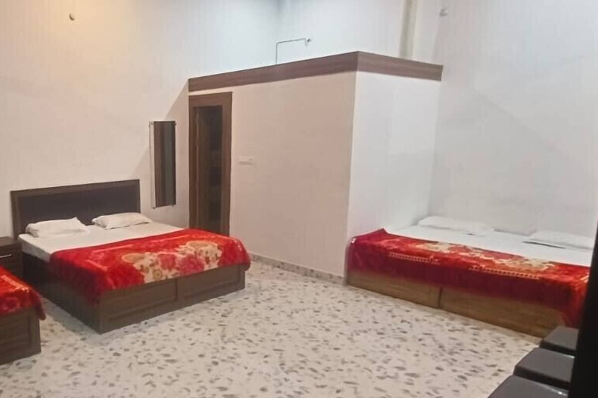 A hotel room with two beds, a small sitting area, and a shower.