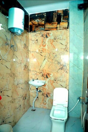 Ein Badezimmer mit Marmorwand, Toilette, Waschbecken und Warmwasserbereiter.