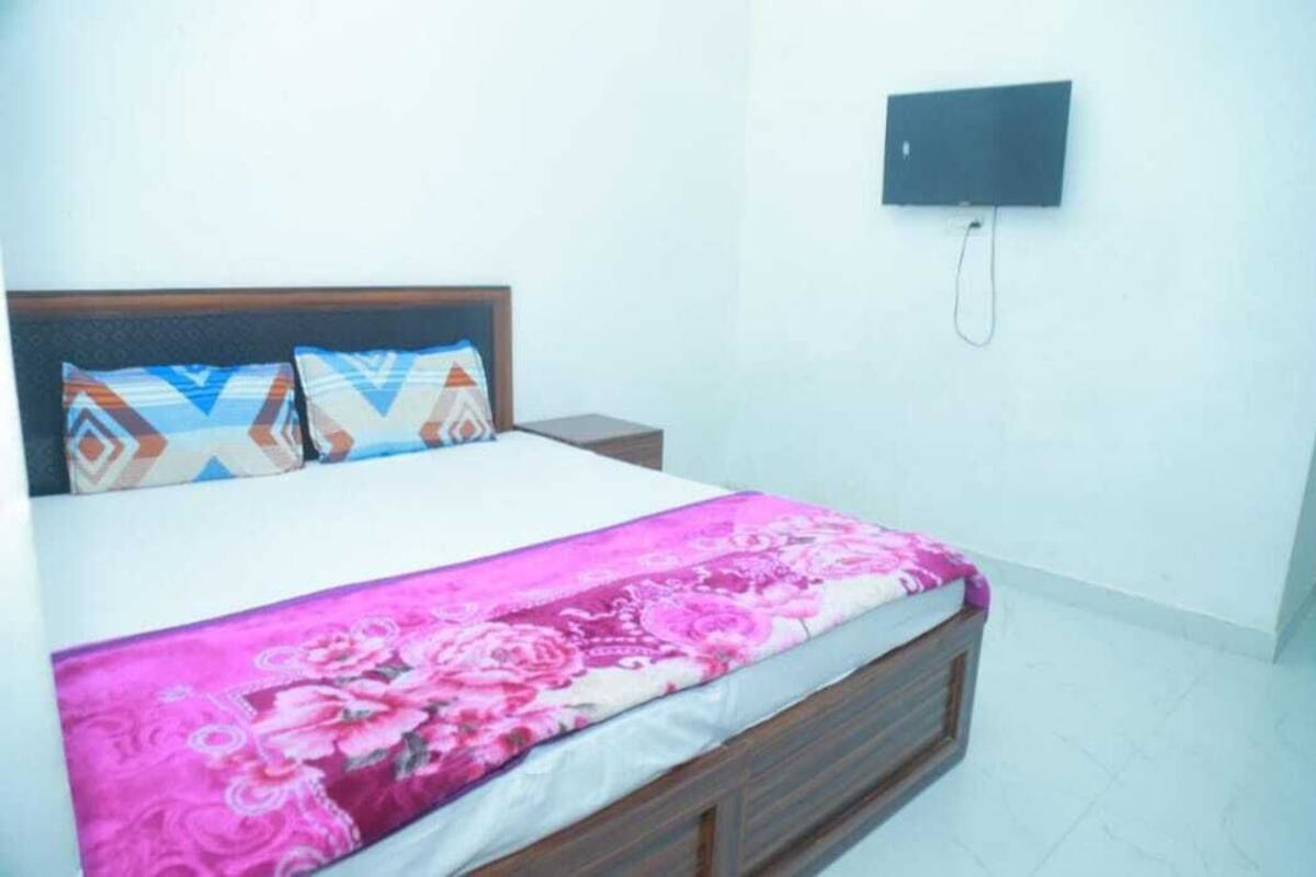 A bedroom with a bed, pillows, a nightstand, and a wall-mounted phone.