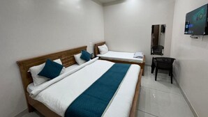Habitación de hotel con dos camas, un escritorio, una silla y un televisor montado en la pared.