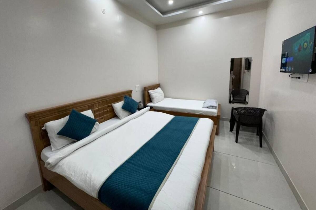 A hotel room with two beds, a desk, a chair, and a TV mounted on the wall.