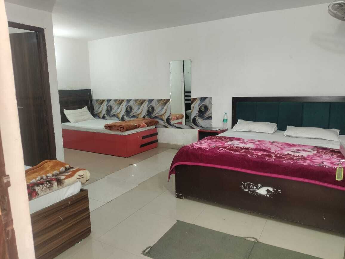 A bedroom with two beds, a mirror, and a red bench.