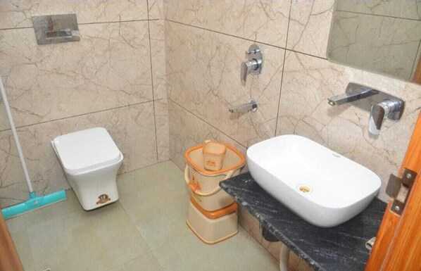 A small bathroom with a toilet, a sink, and a shower. - Nisha Guest Inn (Vrindavan)