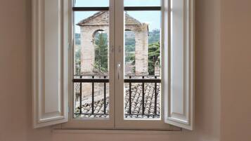 Una habitación con un ventanal que ofrece vistas a un edificio de piedra y un balcón de metal.