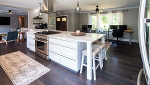 A spacious kitchen with a large island, dark wooden floors, and modern appliances.