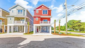 A row of two-story townhouses with balconies, a paved driveway, and a clear sky. - Coastal Beach House, Blocks from Ocean! (Myrtle Beach)