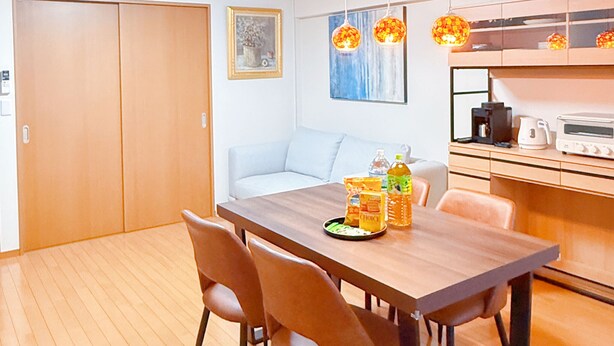 A modern kitchen with wooden cabinets, a dining table with chairs, and a built-in oven. - HYGGE HOUSE Traveler's house (Kashiwa)