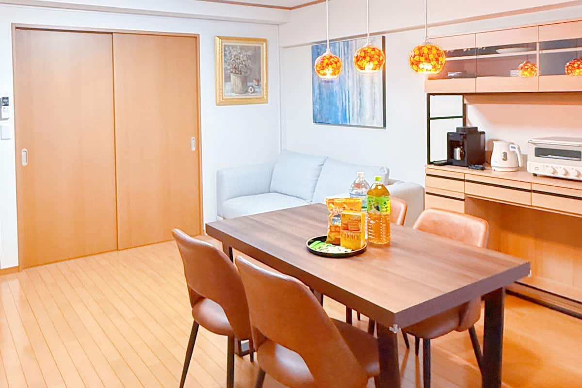 Une cuisine moderne avec des meubles en bois, une table à manger avec des chaises et un four encastré.