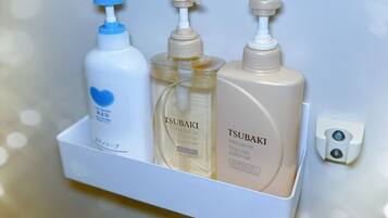 A white shelf with three bottles of hair care products, including a blue pump bottle, a clear bottle, and a beige bottle with a pump.