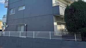 A multi-story building with a flat facade, balconies, and a gated entrance. - HYGGE HOUSE Traveler's house (Kashiwa)