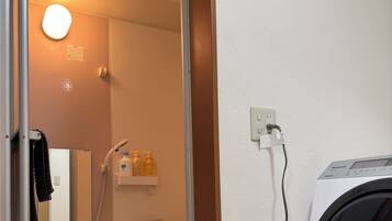 Een badkamer met een wasmachine, een handdoekhouder, een spiegel en een plank met toiletartikelen.