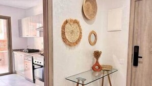 Une cuisine moderne avec des meubles blancs, une table en verre et des œuvres d’art décoratives au mur.