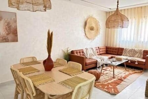 Una sala de estar con un sofá, una mesa de comedor con sillas y una lámpara colgante.