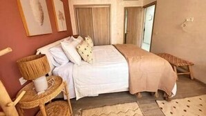 Une chambre à coucher avec un lit, des oreillers, une table de chevet, une chaise et un tapis.