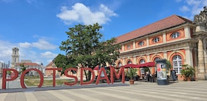 A building with large red letters spelling 'POTSDAM' and a clock tower in the background.