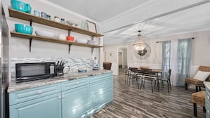 A kitchen with light blue cabinets, a microwave, and wooden shelves holding dishes.