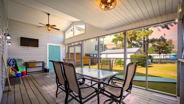 A covered patio with a table and chairs, a ceiling fan, and a view of the backyard.