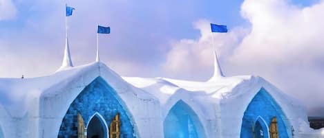 Tres estructuras tipo iglú con interiores azules y puertas de madera, situadas en un paisaje nevado.