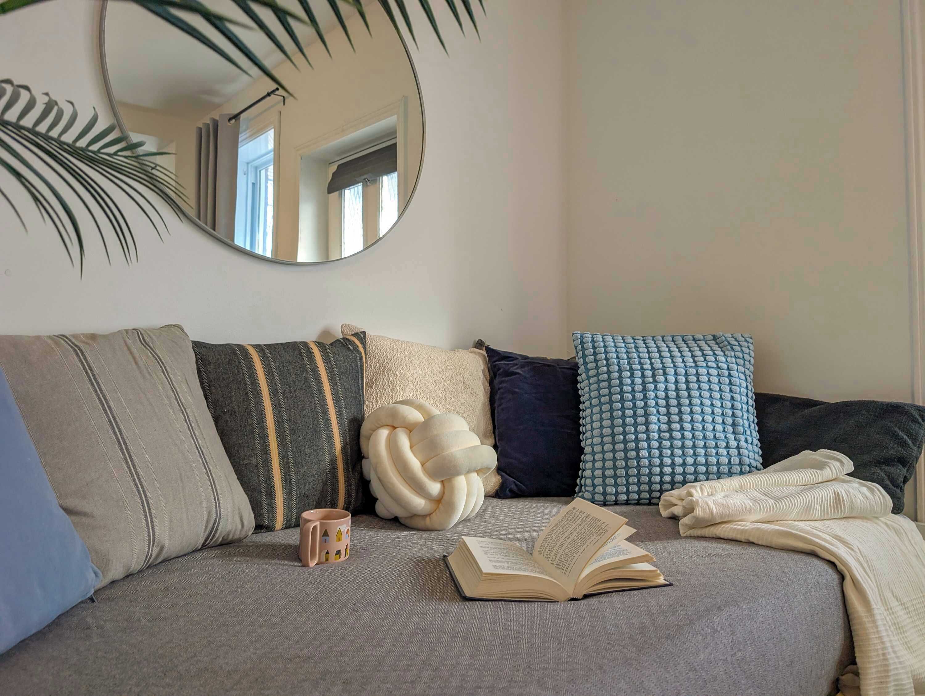 Un salon chaleureux avec un canapé, une tasse de café et un livre ouvert.