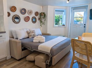 Une chambre moderne avec un lit, une table à manger et une fenêtre donnant sur un beau paysage.
