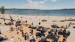 A beachside venue with outdoor seating, umbrellas, and a stage for events.