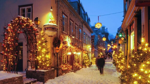 A snow-covered street with Christmas decorations and buildings.