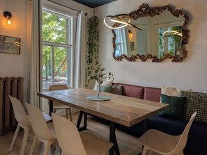 A dining area with a table, chairs, a bench, and a large mirror.