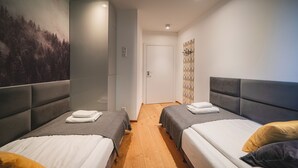 A hotel room with two beds, a wooden floor, a door, and a wall with a forest mural. - Bogdanskiego Residence Sun Snow (Zakopane)