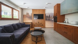 A modern kitchen with wooden cabinets, a built-in oven, and a large window overlooking a balcony. - Bogdanskiego Residence Sun Snow (Zakopane)