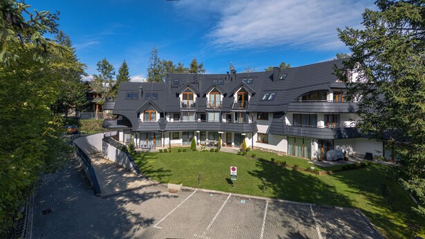 A large, multi-story building with a curved roofline, multiple balconies, and a well-maintained lawn. - Bogdanskiego Residence Sun Snow (Zakopane)