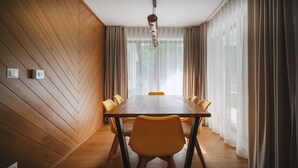 A dining room with a wooden herringbone wall, a wooden table, and yellow chairs. - Bogdanskiego Residence Sun Snow (Zakopane)