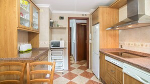 A compact kitchen with wooden cabinets, a microwave, a toaster, and a sink. - Apartment to Enjoy Huelva (Huelva)