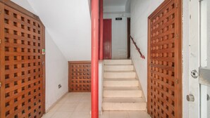 A staircase with a red pipe, wooden lattice doors, and a white wall. - Apartment to Enjoy Huelva (Huelva)