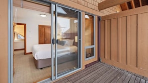 Une chambre à coucher comprenant un lit, une armoire en bois et une porte-fenêtre coulissante donnant sur un balcon.