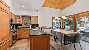 Une cuisine moderne avec des meubles en bois, des plans de travail en granit et un îlot central. On y trouve également un coin repas avec une table et des chaises.