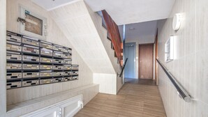 A hallway with a wooden floor, a metal staircase, and a wall-mounted mail rack. - University Apartment (Huelva)