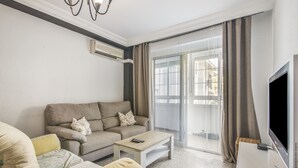 A living room with a sofa, a coffee table, a flat-screen TV, and a sliding glass door. - University Apartment (Huelva)