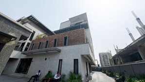 A modern multi-story building with a mix of concrete and brick facades, large windows, and a flat roof. - Glassvine (Lagos)