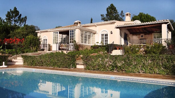 A large house with a swimming pool, a covered patio, and a garden with red flowers. - 2 Bedroom Countryside Villa with Private Pool, Silves (São Bartolomeu de Messines)