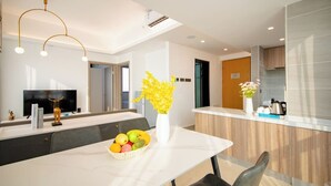A modern kitchen with a dining area, a TV, and a fruit bowl on the table. - Wisdom Forest Hotel (Shenzhen)