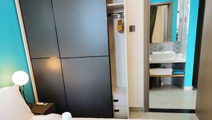A hotel room with a bed, a nightstand with a lamp, a wardrobe, and a bathroom visible through an open door. - Wisdom Forest Hotel (Shenzhen)