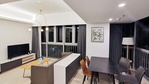 A modern living room with a flat-screen TV, sofa, dining table, and chairs. - Wisdom Forest Hotel (Shenzhen)
