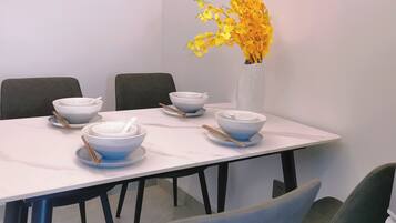 A dining table with white and blue bowls, chopsticks, and a vase with yellow flowers.