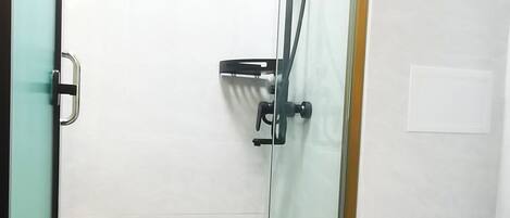 A glass-enclosed shower with a white toilet visible to the right.